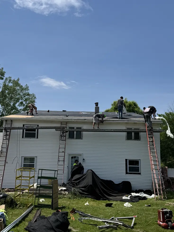 Roof replacement underway on a white two-story home in Western New York