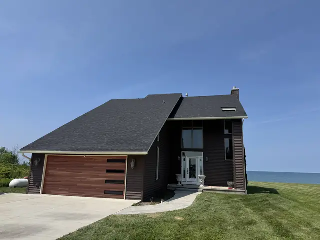 Completed roof replacement on a lakefront Western New York home with cedar garage door