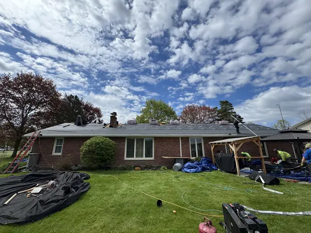 Roof tear-off day with materials staged in the backyard of a WNY home