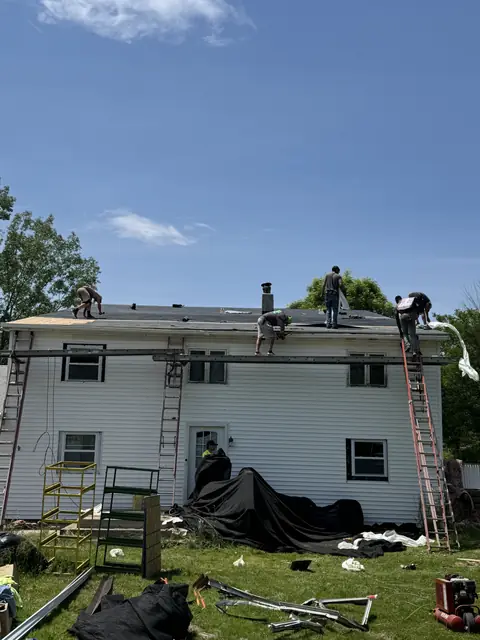 Roof replacement underway on a white two-story home in Western New York