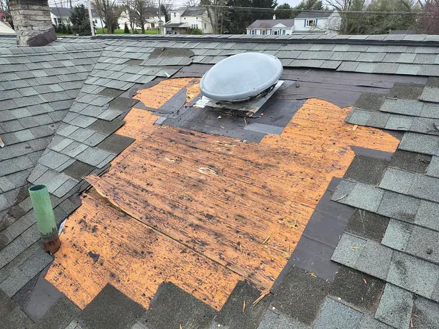 Roof tear-off exposing plywood decking around a roof vent during a WNY replacement