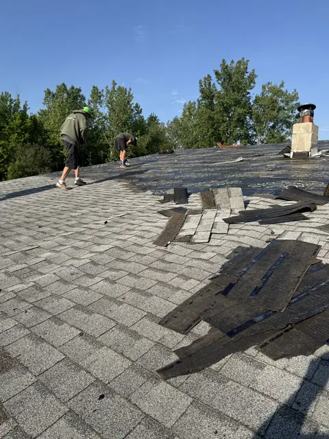 Roof tear-off in progress with old shingles being stripped to the deck